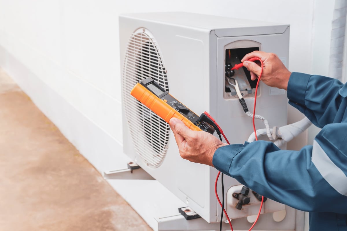 Technician repairing a central air conditioning system outdoors