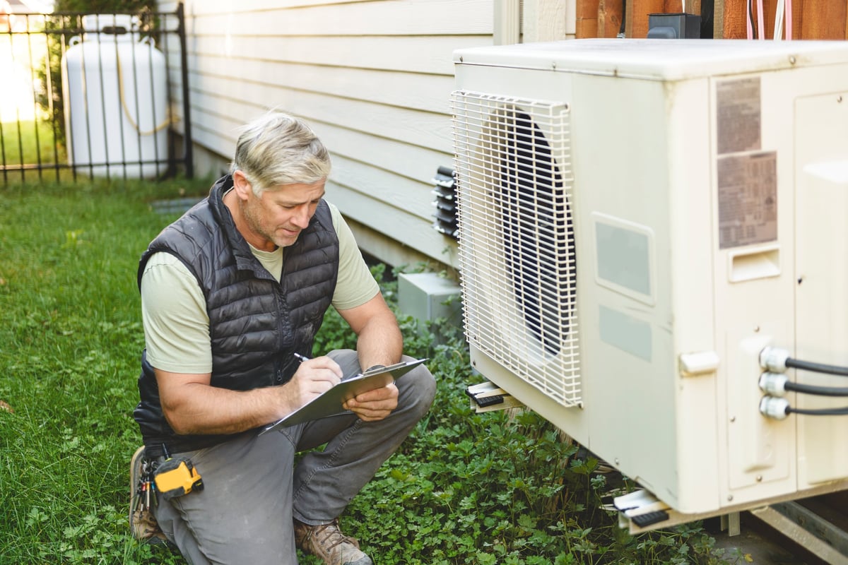 Technician working on an outdoor air conditioning and heat pump unit